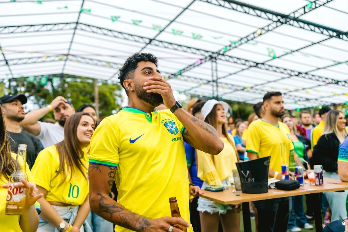 Grupo de torcedores com camisas amarelas da seleção brasileira reunidos animados para assistir ao jogo do Brasil
