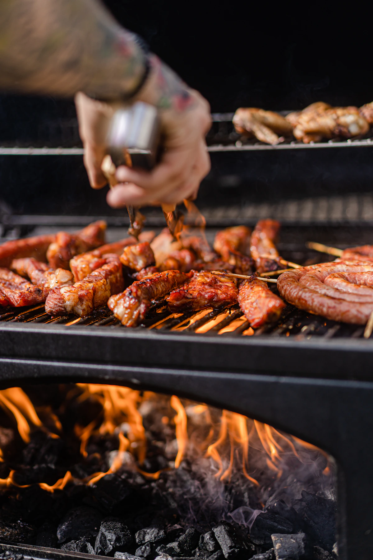 Pessoa grelhando carne na churrasqueira, com as mãos manuseando a peça sobre a brasa em close no processo de preparo